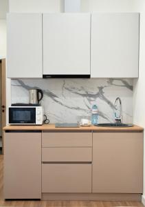 a kitchen with white cabinets and a microwave at Q Apartment in Almaty +28 photos