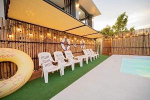 a group of white chairs sitting next to a fence at Luxury Chill Pool Villa in Pattaya Central