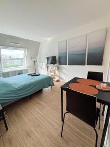 a bedroom with a bed and a table and a dining room at Studio moderne en bord de mer in Cabourg
