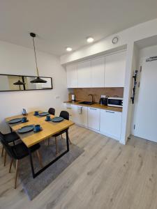 a kitchen and dining room with a table and chairs at Przytulny Apartament 406 IV piętro in Kołobrzeg +8 photos