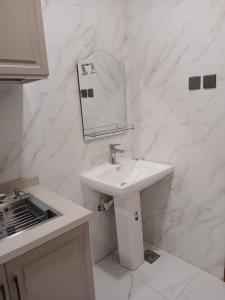 a white bathroom with a sink and a mirror at روضة طيبة السكنية شقة قريبة من الحرم in Al Madinah +5 photos