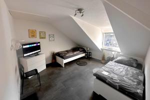 a attic room with a bed and a television at VAZ Apartments Freiheit 1 für Monteure und Fachkräfte, Küche, Balkon, TV, WLAN, Parkplatz, Autobahnähe in Remscheid
