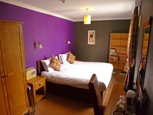 a bedroom with a bed with a purple wall at Argyll Hotel in Ullapool