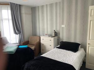 a small bedroom with two beds and a chair at Villa Guest House in Porthcawl