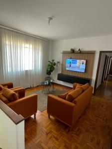 a living room with two couches and a flat screen tv at Casa da Serra in Poços de Caldas