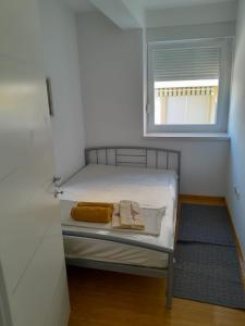 a small bedroom with a bed and a window at Apartman Novalja - Put Lokvice in Novalja