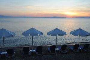 un gruppo di sedie e ombrelloni sulla spiaggia di Symmetron Suites a Kálamos