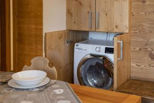 eine Waschmaschine und ein Trockner in einer Küche mit einem Tisch in der Unterkunft Chalet Diamond - AffittiPontediLegno in Ponte di Legno + 3 Fotos