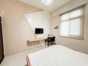 a bedroom with a bed and a desk with a television at 澎湖樂在綺中民宿 第580號 in Magong