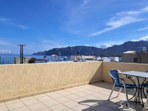 een tafel en stoelen op een balkon met uitzicht op de oceaan bij Koxylia apts in Mochlos