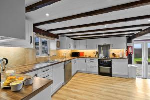 a large kitchen with white cabinets and wooden floors at Finest Retreats - Cowslip in Bradworthy