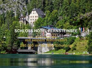 um edifício sobre uma colina ao lado de um corpo de água em Schloss Hotel Fernsteinsee em Nassereith