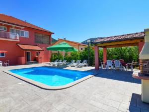 a swimming pool in a yard with chairs and a house at Holiday Home Amaya in Vrgorac