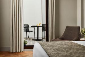 Un dormitorio con una cama, una silla y una mesa. en NH Collection Amistad Córdoba, en Córdoba