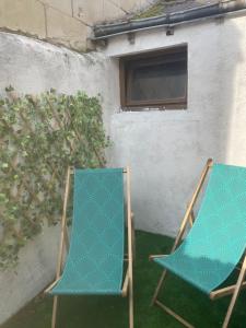 two chairs sitting on the grass in front of a building at Petite maison de ville in Sainte-Maure-de-Touraine +1 photo