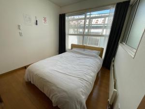 a white bed in a room with a window at Hakodate cozy house w/parking in Hakodate