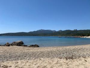 une plage avec des rochers, de l'eau et des montagnes en arrière-plan dans l'établissement B&B Tanda Rooms Olbia, à Olbia