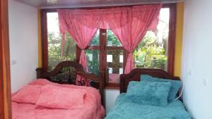 two beds in a room with a window at Perla del Ruiz in Manizales