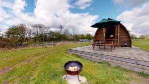 a small wooden cabin with a grill and an umbrella at Hill Farm and Orchard in Leighton Buzzard
