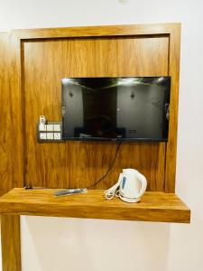 a tv on a wall with a coffee cup on a wooden shelf at Hotel shree park in Faizābād +19 photos