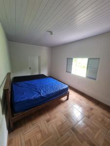 a bedroom with a blue bed in a room with a window at Chácara Falcão in Itapeva