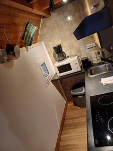 a small kitchen with a refrigerator and a microwave at Calmos Cottage in Barneville-Carteret
