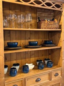 a wooden hutch with blue bowls and glasses on it at Christmas Cottage in Doveridge