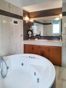 Una gran bañera blanca en un baño con lavabo. en Silver Moon Villa, en Achlia