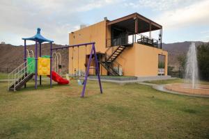 a park with two playground equipment in front of a building at Green Meadows Farmhouse in Minazif