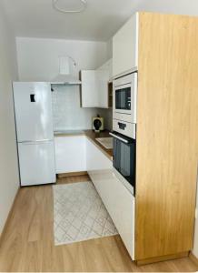 a kitchen with white appliances and a wooden floor at Apartmán s parkovacím miestom in Nitra