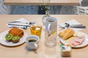 a table with two plates of food and a glass of wine at Appart'City Classic Reims Parc des Expositions in Reims