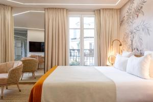 ein Hotelzimmer mit einem Bett und einem großen Fenster in der Unterkunft Grand Hotel Saint Michel in Paris