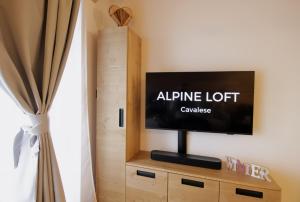a flat screen tv sitting on top of a wooden cabinet at ALPINE LOFT - Agenzia Dolomiti Affitti in Cavalese