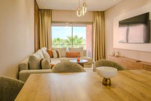 ein Wohnzimmer mit Tisch und Couch in der Unterkunft Luxury 2BD in Prestigia Jade with Pool and Golf View in Marrakesch