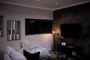 a living room with a couch and a flat screen tv at Eliá Dendró Víla in Lydenburg