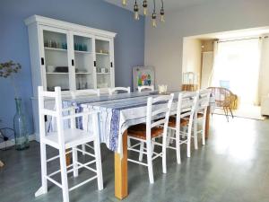 a dining room with a table and white chairs at Quatre Vents Saint Hilaire de Riez in Saint-Hilaire-de-Riez