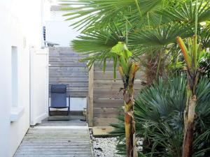 une passerelle en bois avec une chaise bleue et des palmiers dans l'établissement Dauphin Saint Gilles Croix de Vie, à Les Bussolleries 2 autres photos