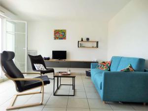 a living room with a blue couch and two chairs at Gardénia Saint Gilles Croix de Vie in Le Sablais