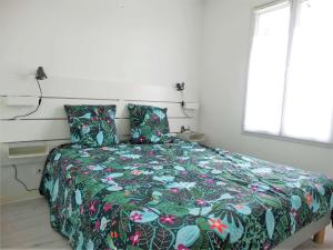 a bedroom with a bed with a colorful comforter and a window at Gardénia Saint Gilles Croix de Vie in Le Sablais
