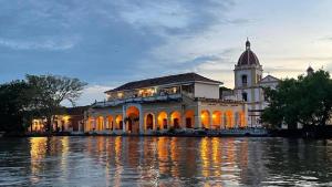 a building with a clock tower next to a body of water at Hotel Santa Bárbara Mompox Doble in Mompos