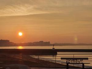 a sunset over a body of water with a bench at Le Mistral Saint Gilles Croix de Vie in Les Bussolleries +10 photos