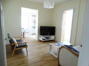 a living room with a flat screen tv and a chair at Javeline Saint Hilaire de Riez in Sion-sur-lʼOcéan