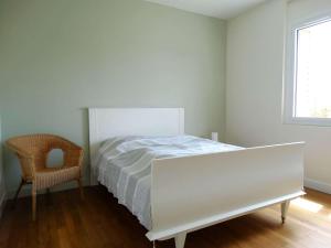 a white bedroom with a bed and a chair at Javeline Saint Hilaire de Riez in Sion-sur-lʼOcéan