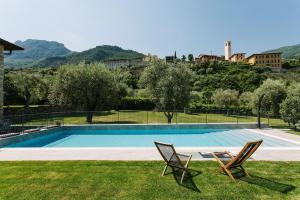 a swimming pool with two chairs in the grass at PELACA' Resort in Gargnano