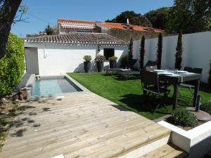 Transat Saint Gilles Croix de Vie في سانت جيل كروا دي فيي: حديقة خلفية مع طاولة وطاولة ومسبح