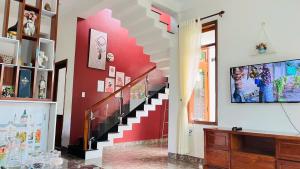 a staircase in a living room with a red wall at Vang's Homestay - Huế in Ấp Long Hồ Hạ