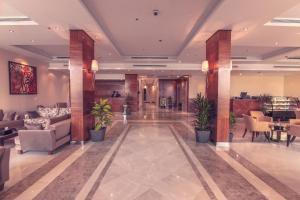 a lobby with couches and plants in a building at Nawaress Hotel in Jazan