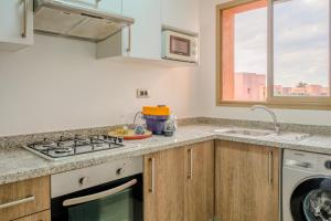eine Küche mit einem Herd, einem Waschbecken und einem Fenster in der Unterkunft Luxury 2BD in Prestigia Jade with Pool and Golf View in Marrakesch