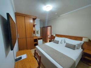 a bedroom with a large white bed and a table at Hotel Tenda in Marília