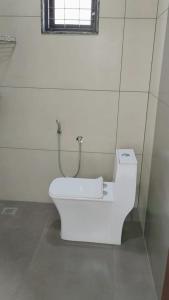 a white toilet in a bathroom with a window at Vaango Cottages in Idukki +10 photos